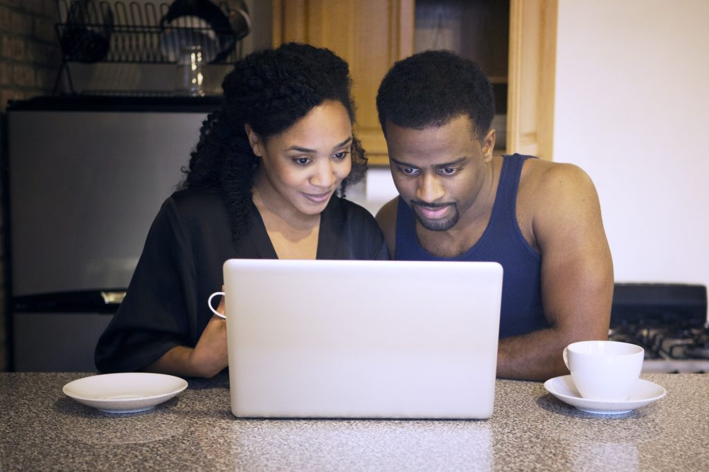 Couple Looking At Laptop Computer In Kitchen